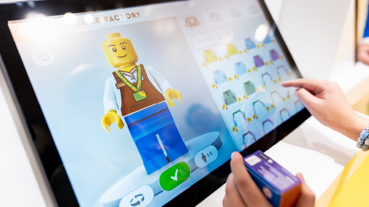 a-person-interacts-with-a-touch-screen-at-a-lego-minifigure-factory-kiosk-to-design-a-custom-minifigure-wearing-the-hidden-disabilities-sunflower-lanyard.webp