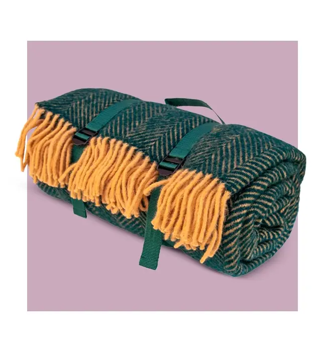 A rolled-up green and yellow herringbone picnic blanket with adjustable carrying straps and a handle for easy transport