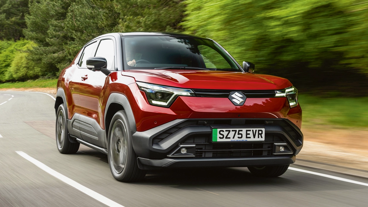 A red Suzuki eVitara driving down a country road