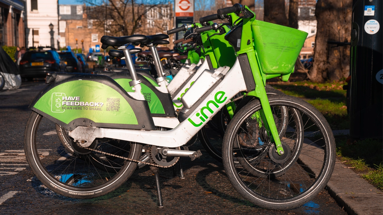 A row of green and white electric Lime Bikes parked on a city street, representing shared urban mobility options.