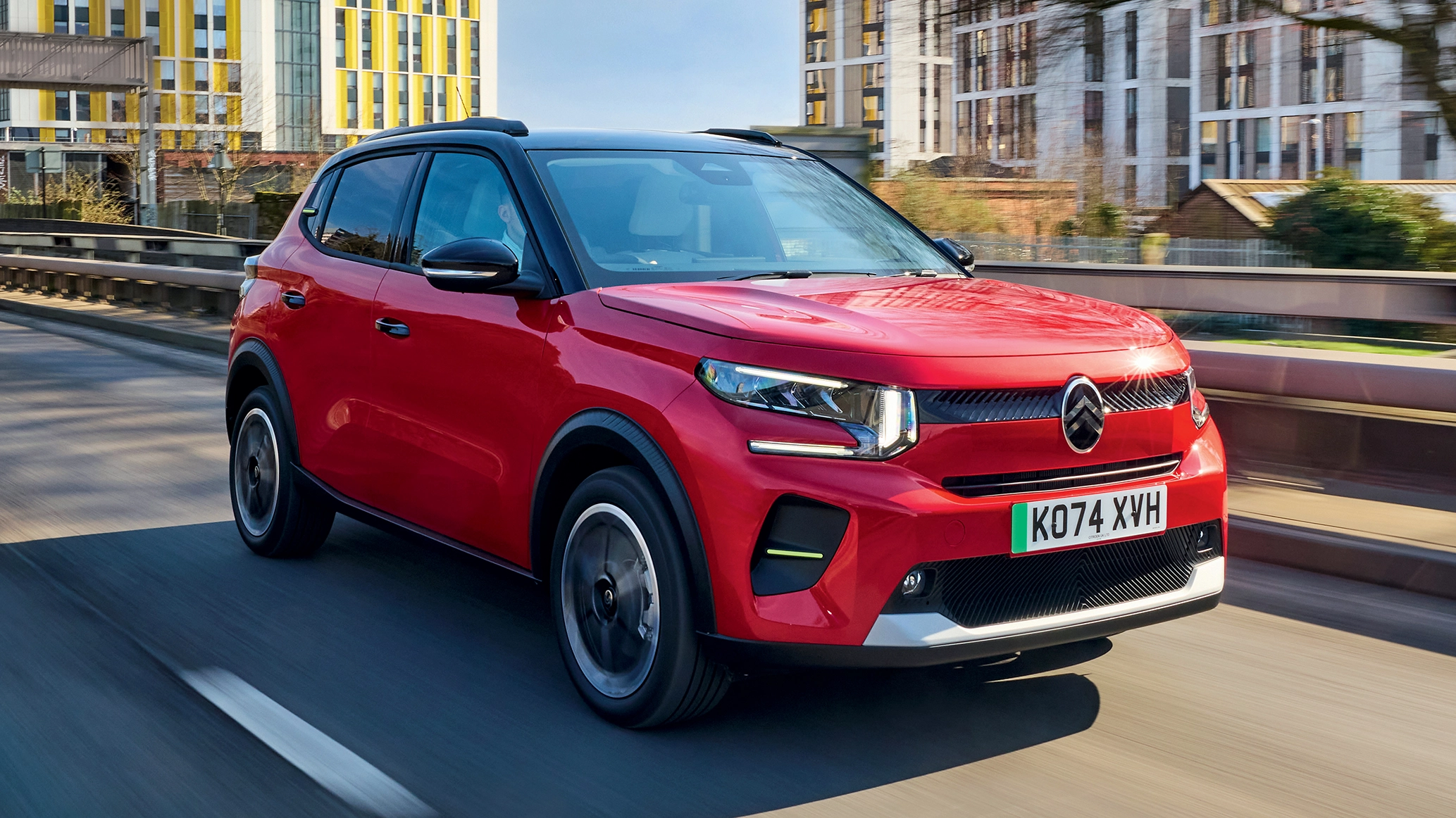 A Citroen E-C3 driving in an urban landscape
