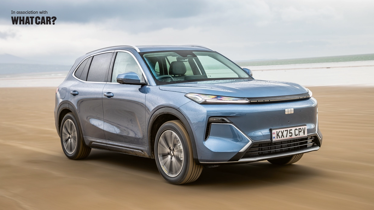 A blue Geely Starray SUV driving across a sandy beach, with "In association with What Car?" text in the top left corner.