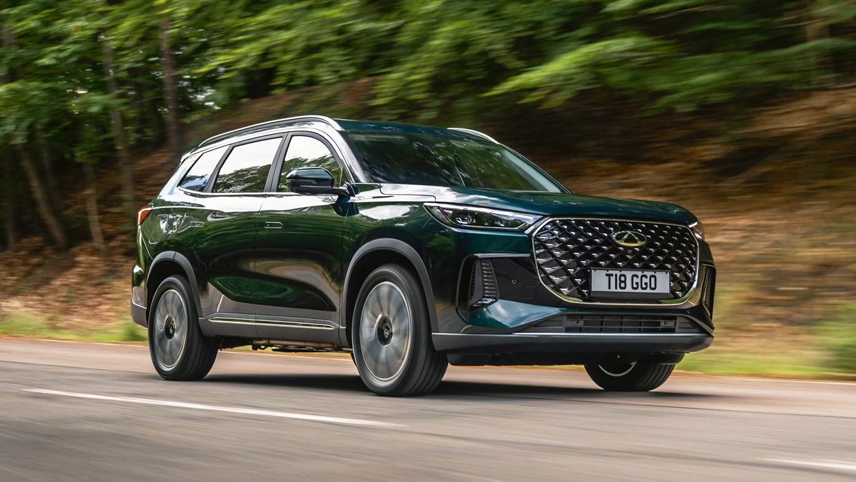 Dark green Chery Tiggo 8 Pro SUV driving on a tree-lined road