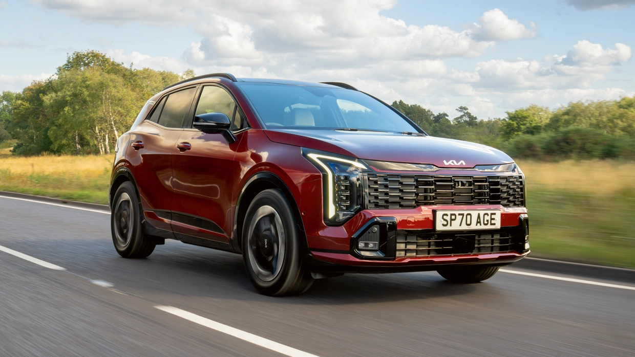Maroon Kia Sportage SUV driving along a rural road.