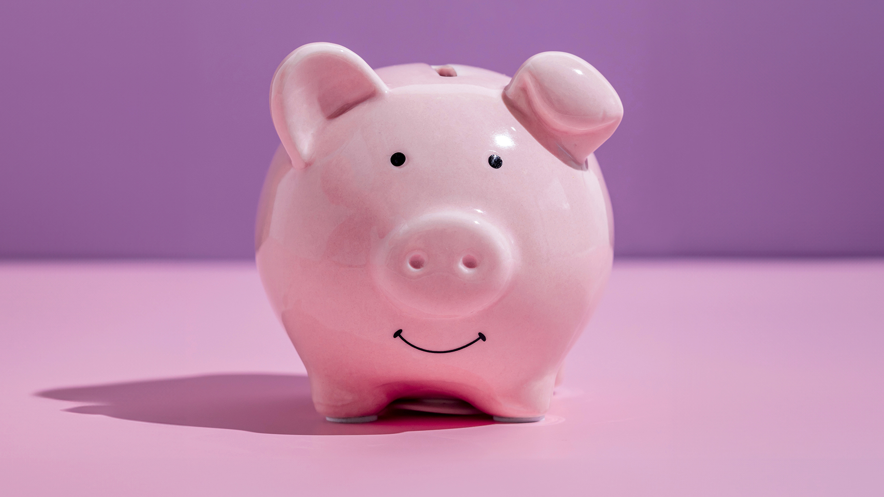 A pink piggy bank in front of a pink background