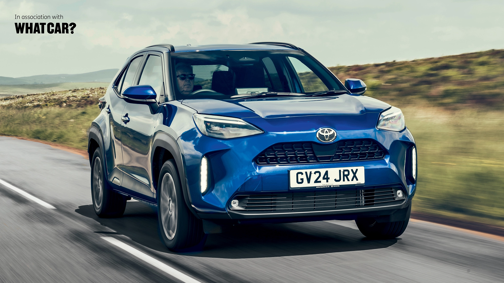 A Toyota Yaris Cross driving down a country road