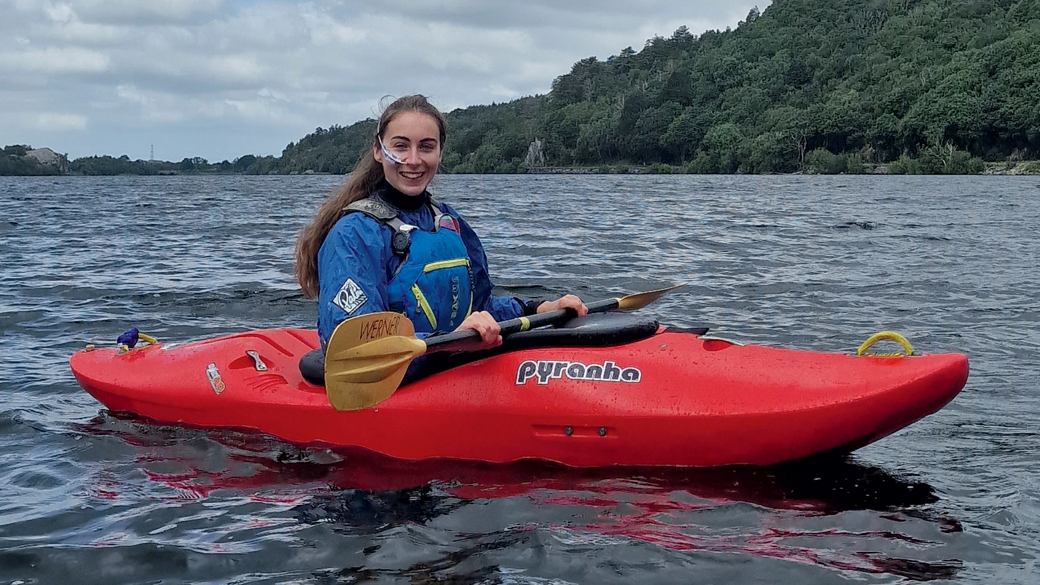 Bethany in a red Kayak at Llyn Padarn smiling at the canera