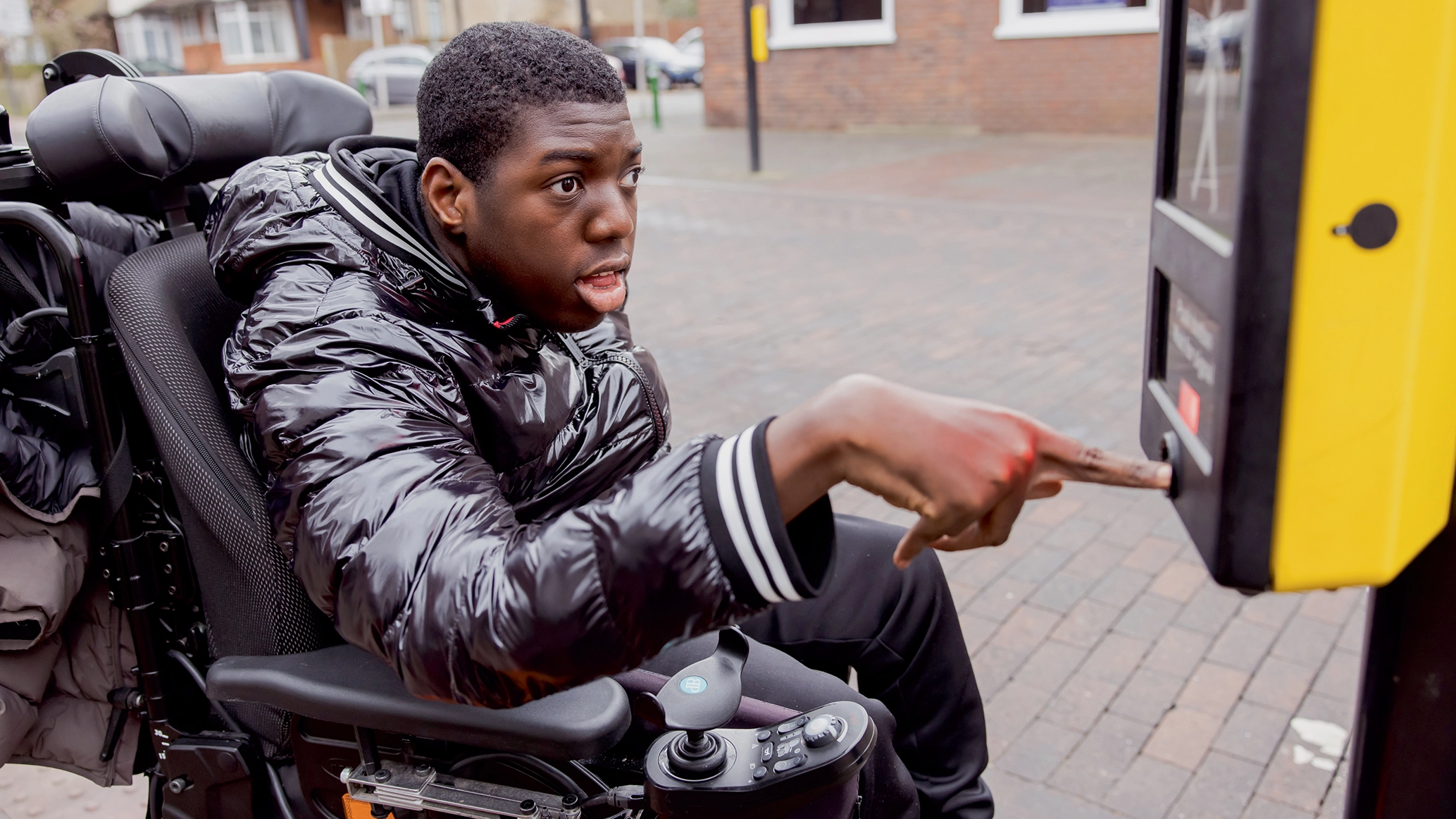A visually impaired young wheelchair user using a pedestrian crossing