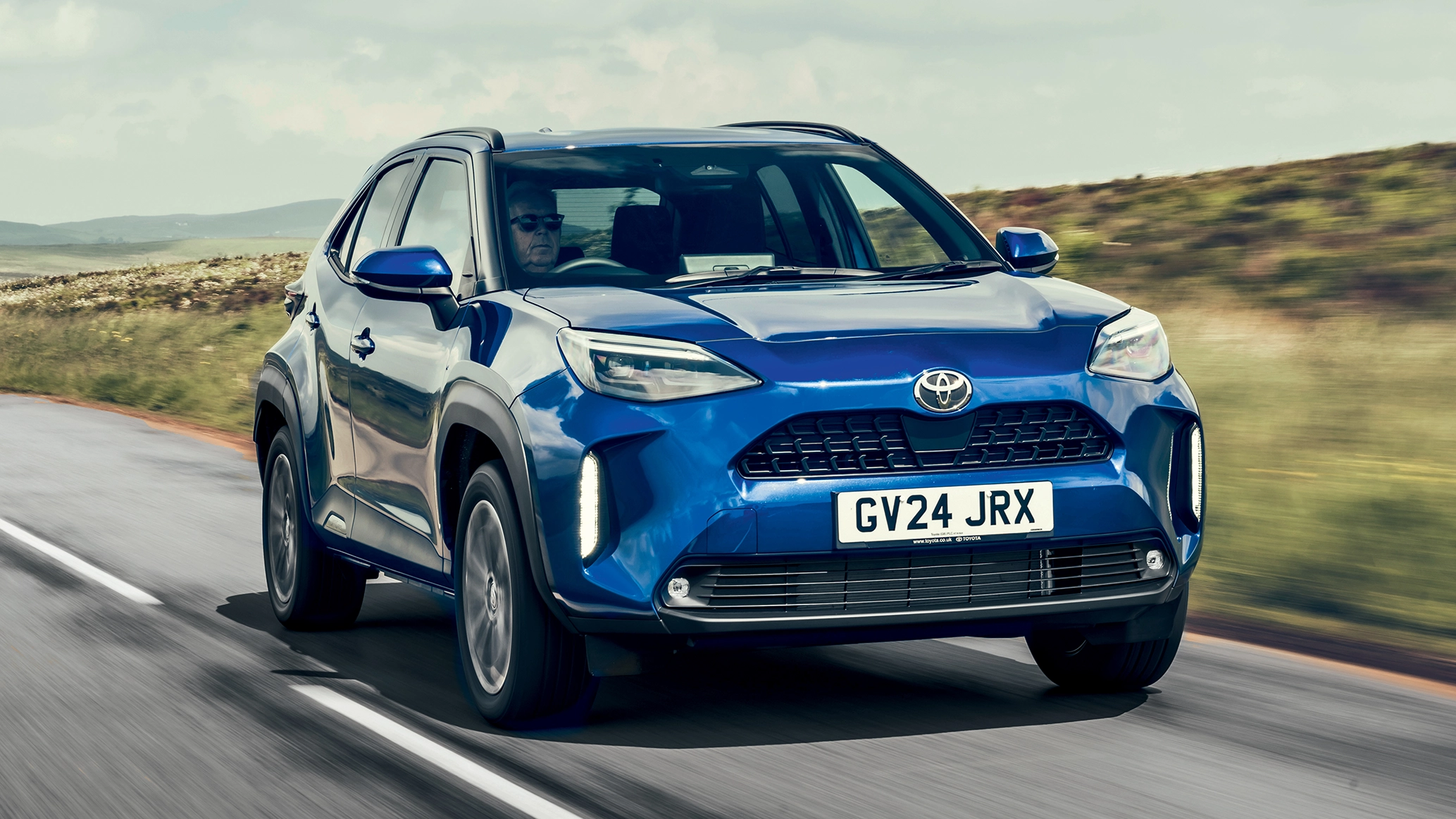 A Toyota Yaris Cross driving down a country road