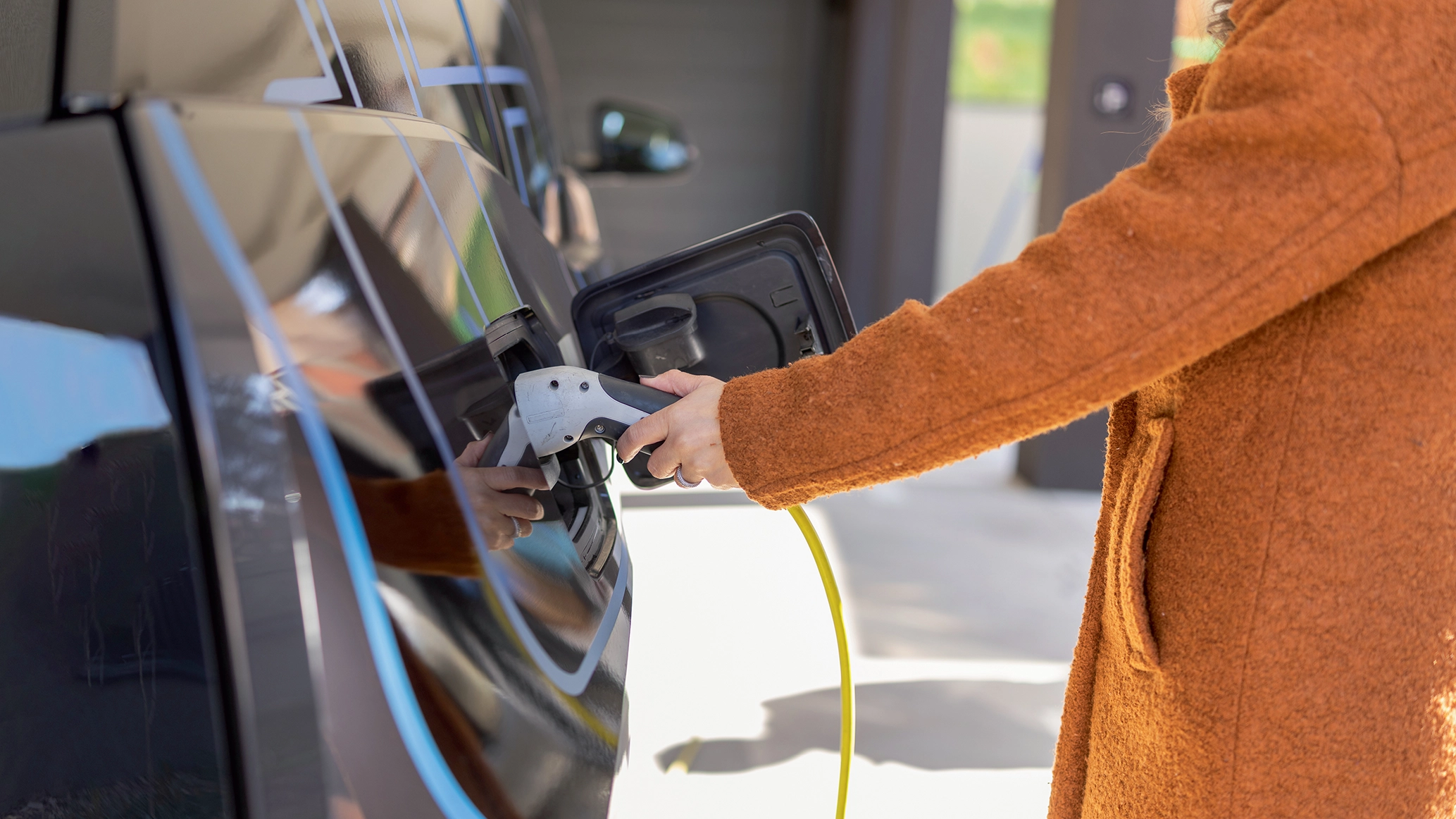 A close-up image of someone plugging an EV into a fast-charger