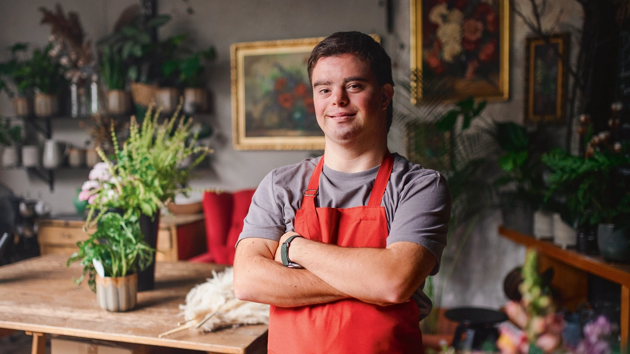 A man with Down Syndrome wearing an apron and crossing his arms