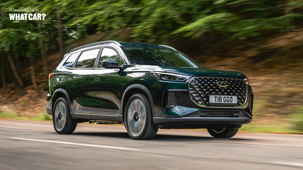 Dark green Chery Tiggo 8 Pro SUV driving on a tree-lined road, with "In association with What Car?" text in the top left corner