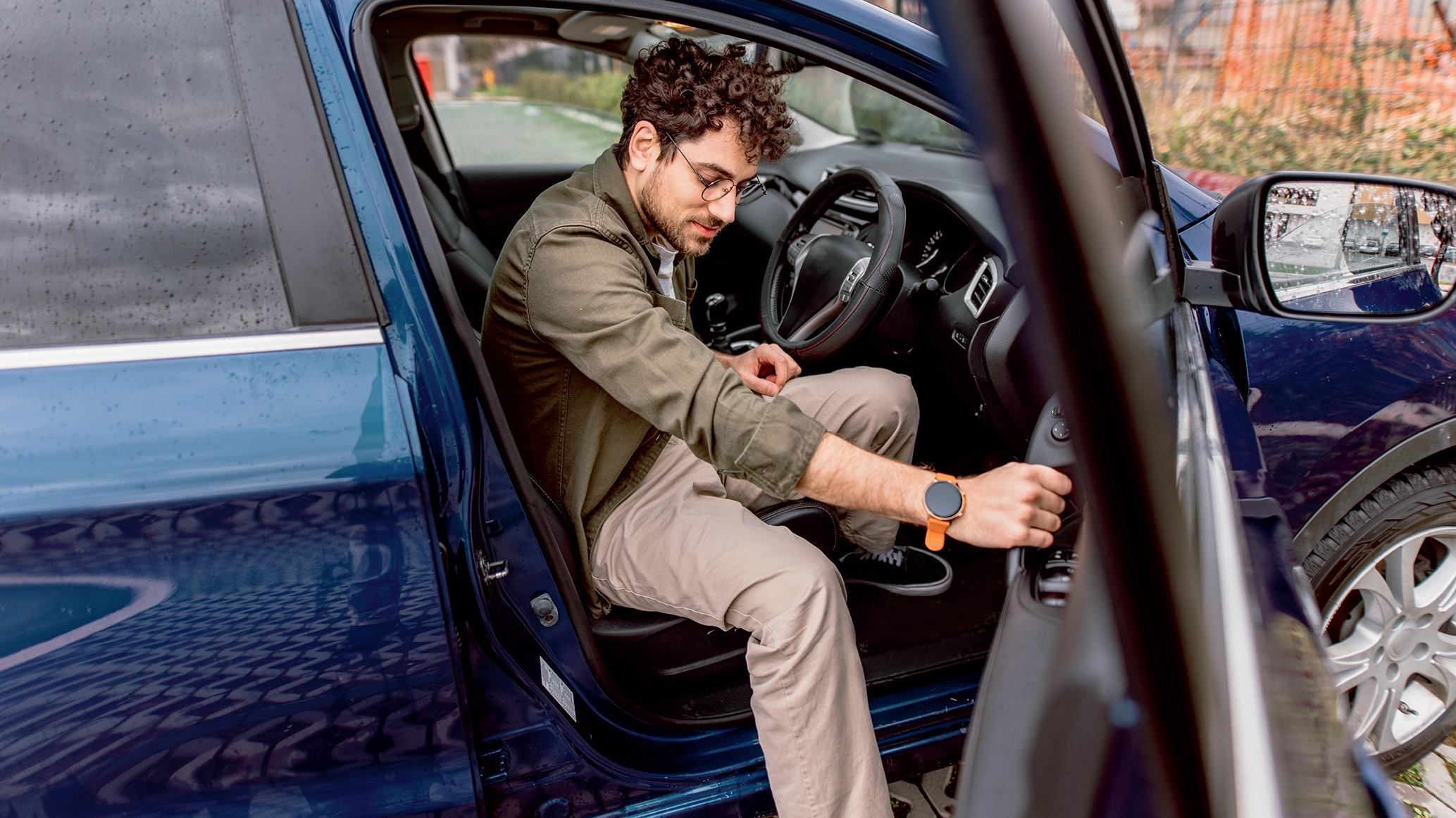A male driver, under 30, stepping out of his car.